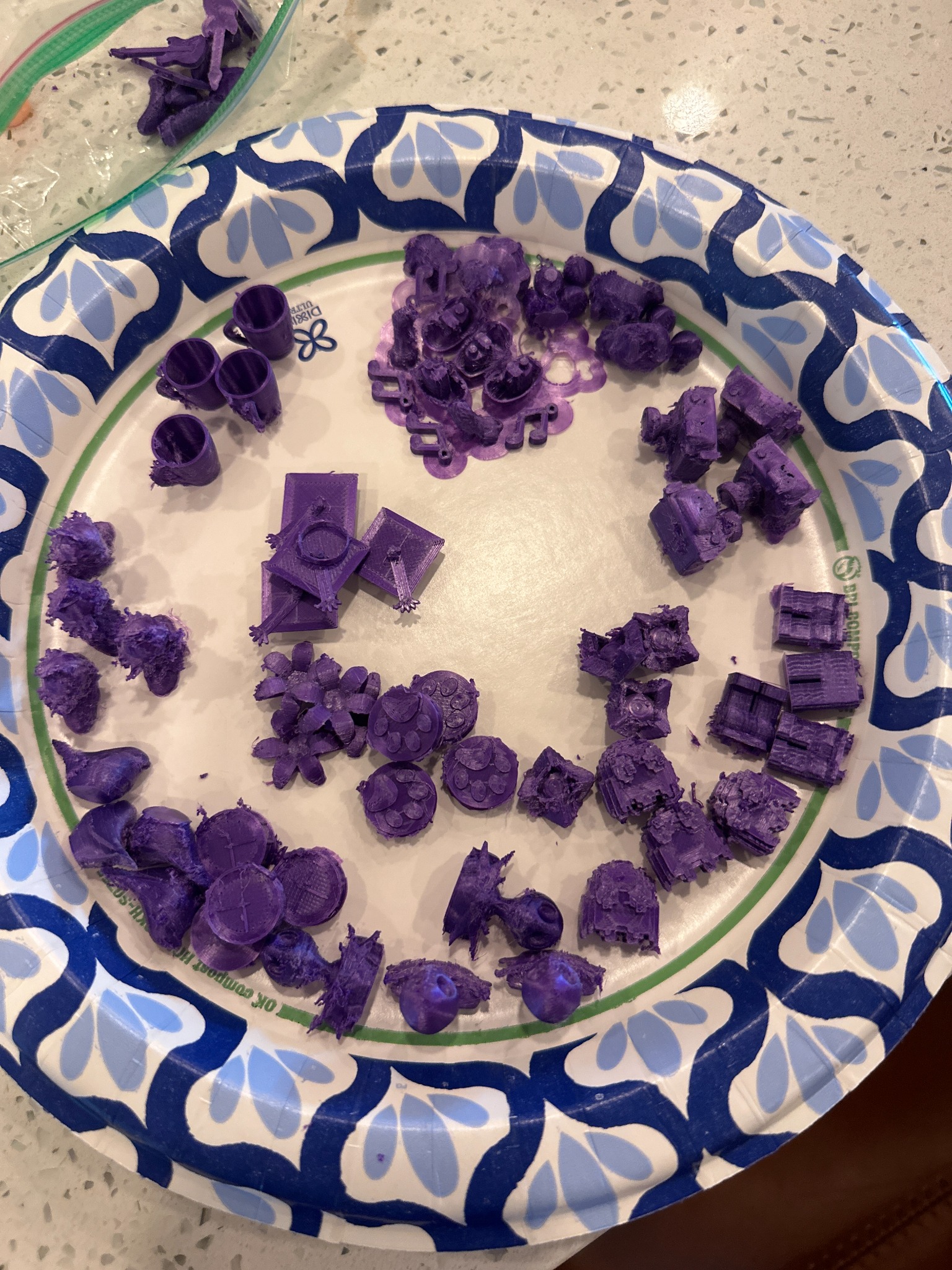 Paper plate full of purple prototype pieces including cups, flowers, ghosts, skulls, houses, and animals