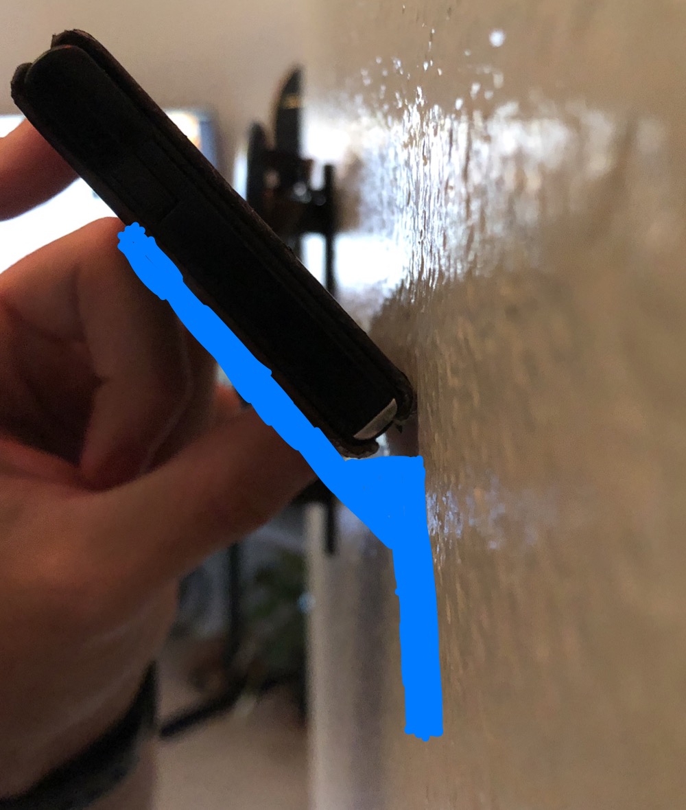 Hand holding wallet against wall with blue wedge shape drawn showing initial angle concept